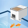 Mangeur automatique WiFi blanc pour aquarium avec de la nourriture et des poissons orants.