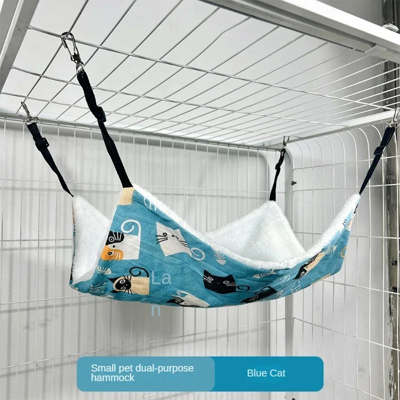 Ein blauer Katzenhimmel hängt in einem Drahtkäfig mit Katzenillustrationen.