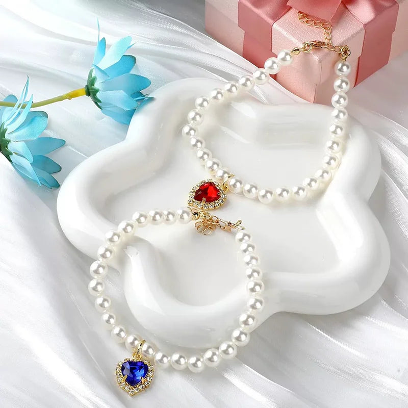 Un délicat collier de perles avec un pendentif de pierre rouge est présenté sur un plat en céramique blanche.
