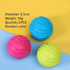 Three rubber chew toys in blue, pink, and yellow are displayed on a light blue surface.