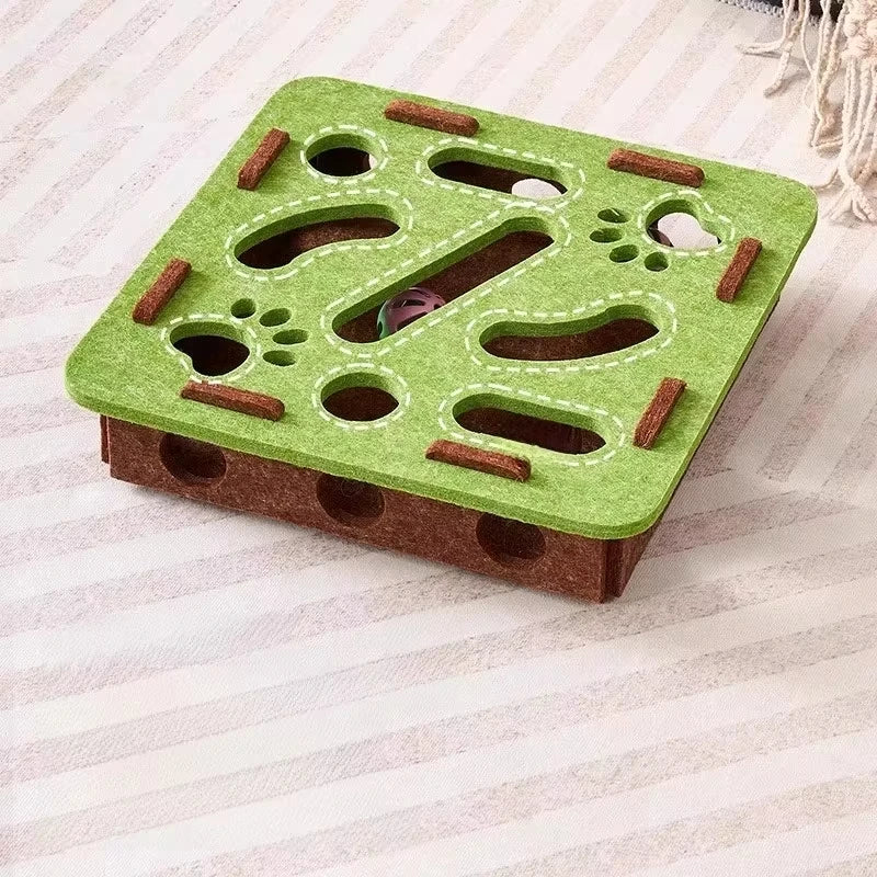 A green puzzle toy for cats with various holes and tunnels made of felt and wood.