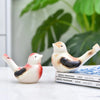 Keramisches Wasservogel-Signalhorn in Weiß und rötlich-orange Farben auf einem Stapel Bücher.