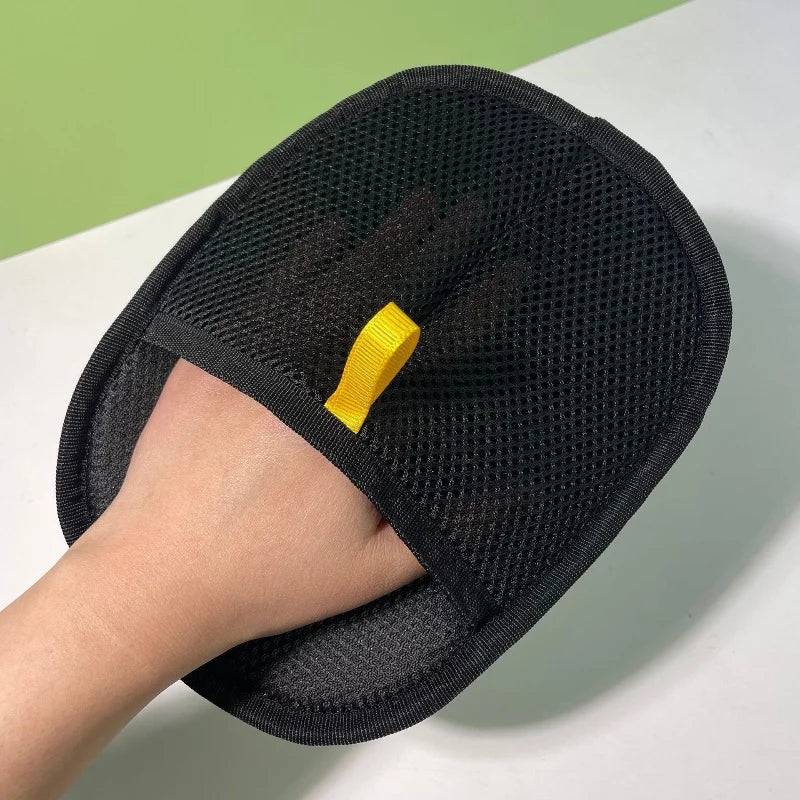 Eine Hand trägt schwarze Fellentfernerhandschuhe für Katzen und Hunde, die die strukturierte Netzmaterial zeigen.