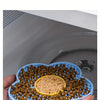 A hand holds a silicone lick mat filled with brown pet food, ready to be heated in an oven or microwave.