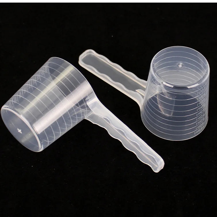 A transparent pet measuring spoon with a scale for dog and cat food is shown on a dark background.