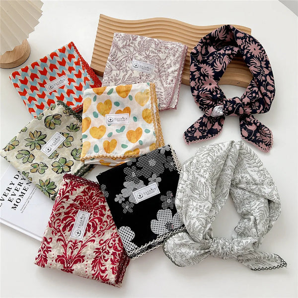 Collection de foulards en coton classiques à motifs floraux et variés, disposés sur une surface blanche.