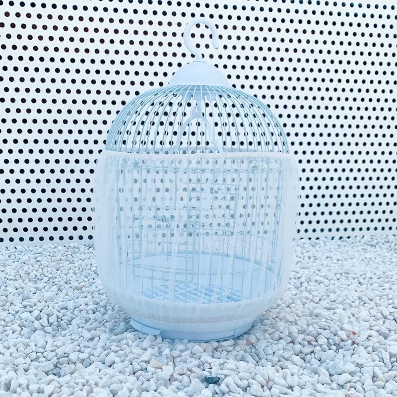 Clear breathable nylon mesh bird cage seed guard with a dome top resting on white gravel.