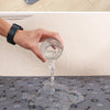 A hand pours water from a glass into a pet pee pad for washing.
