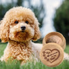 A fluffy golden-colored dog lies in green grass next to a wooden keepsake box with paw prints engraved on it.
