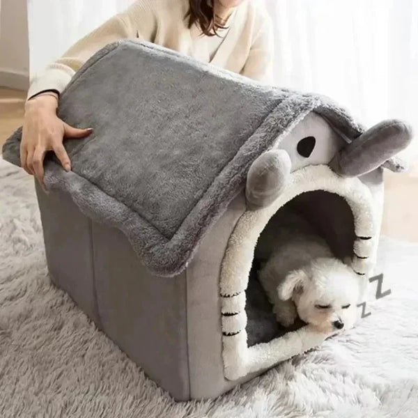 A gray pet house with a soft, fuzzy entrance for a small white dog is shown on a fluffy rug.