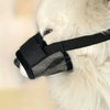 A black adjustable soft dog muzzle is being worn by a white fluffy dog.