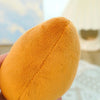 A close-up of an orange avocado plush toy with a stitched seam, held in a hand.