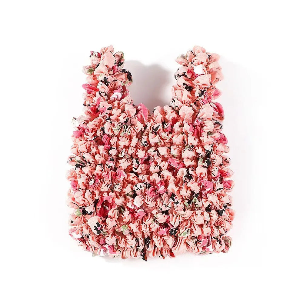 A close-up of a reusable foldable bubble shopping bag made of pink and red floral fabric.
