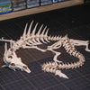 A white articulated dragon skeleton model displayed on a dark surface with a grid background.