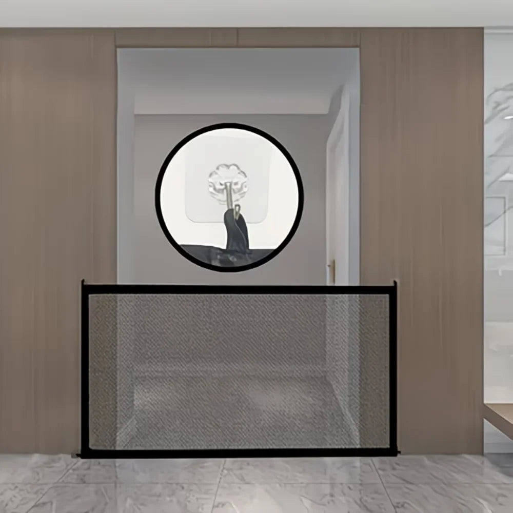 A black mesh foldable pet gate or barrier fence is displayed in a modern interior setting.