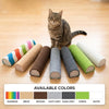 A tabby cat sits among various colored cylindrical scratching posts on a wooden floor.