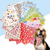 A pile of colorful cotton triangle bandanas for dogs and cats next to a dog.