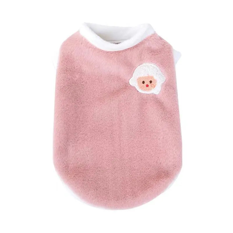 A soft pink knitted pet vest with a white embroidered face detail.