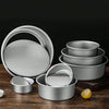 A set of round aluminum cake pans stacked and displayed on a wooden surface.