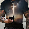 A man wearing a dark t-shirt with a graphic cross design, holding a smartphone.