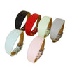 A collection of wide leather dog collars in various colors including black, red, light green, and beige.