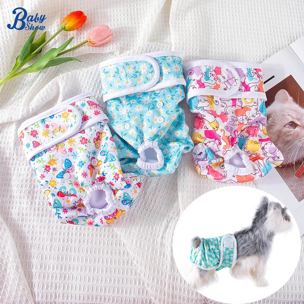 Reusable female dog diapers in various floral patterns with elastic closures shown next to a small kitten.