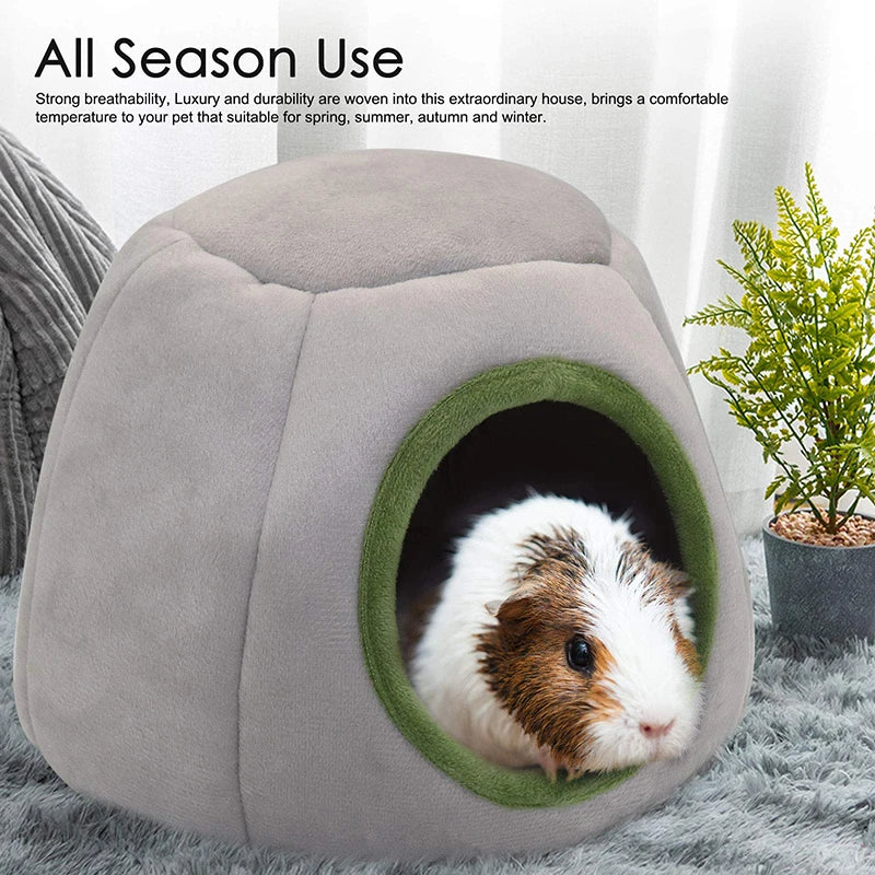 A gray plush cave bed for small pets is shown with an entrance, featuring a fluffy white and brown pet.
