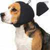 A dog wearing a black calming headgear and a separate black ear cover.