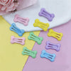 A collection of bone-shaped hair clips for pet grooming in various pastel colors like pink, yellow, blue, and green.