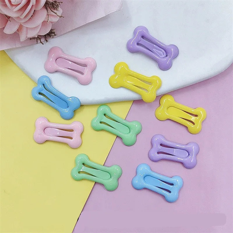 A collection of bone-shaped hair clips for pet grooming in various pastel colors like pink, yellow, blue, and green.