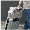 A person is carrying a gray portable pet carrier bag with a fluffy white dog peeking out.