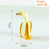 A light yellow resin sculpture of a duck with a long beak and body, shown against a white background.