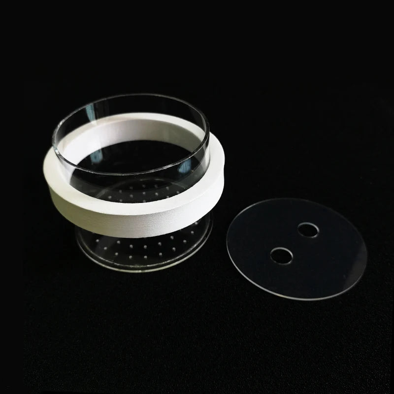 A white isolation box for aquarium fish breeding with suction cups and a clear lid resting on a black surface.