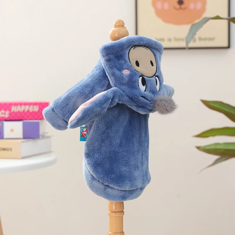 A plush toy of a blue dog wearing a hoodie is displayed on a wooden stand.