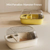 A yellow plastic hamster food and water habitat cage is shown on a light wooden surface.