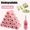 A stack of pink biodegradable pet garbage bags and a green dispenser for dog waste bags.