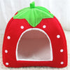 A bright red strawberry shaped hideaway rabbit bed and hay feeder set with green leaves and white polka dots