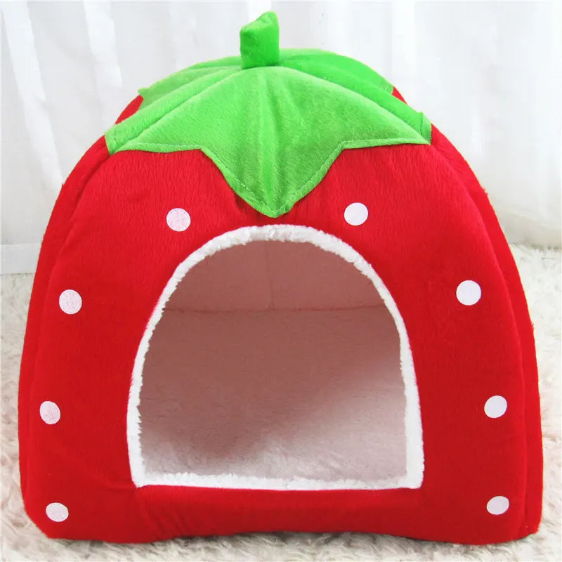 A bright red strawberry shaped hideaway rabbit bed and hay feeder set with green leaves and white polka dots