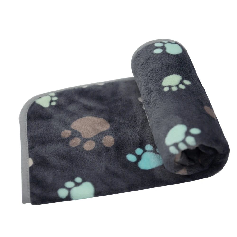 A rolled waterproof dog blanket with a dark gray background and light teal paw prints.