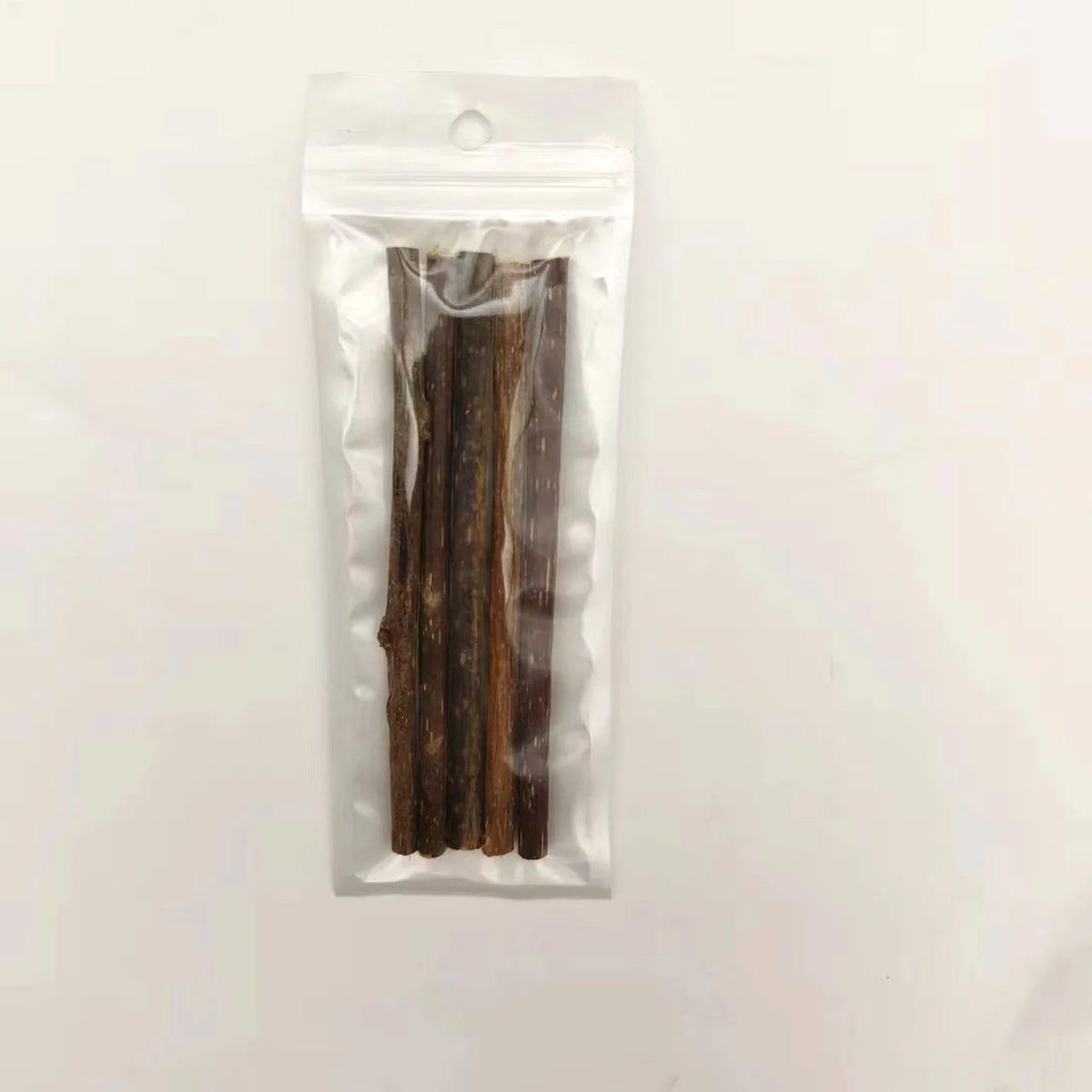 A clear plastic bag containing several dark brown natural herbal cat chew sticks.