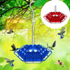 A hanging hummingbird feeder with a blue hexagon design and a red hexagonal feeding area, suspended from a tree branch.