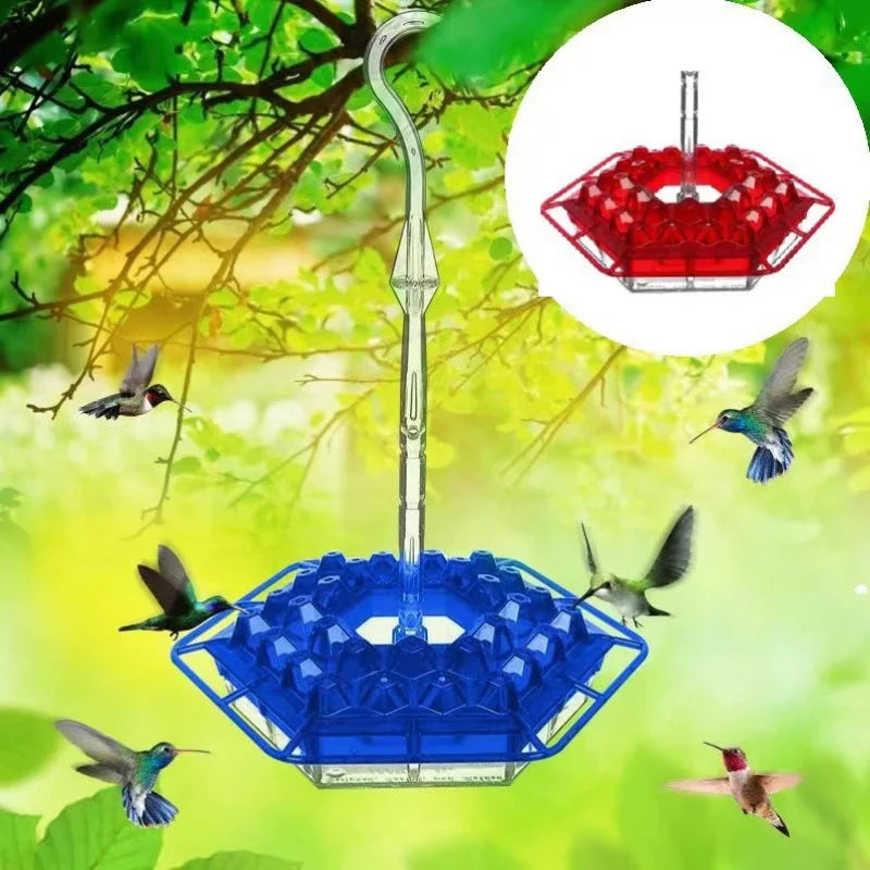 A hanging hummingbird feeder with a blue hexagon design and a red hexagonal feeding area, suspended from a tree branch.