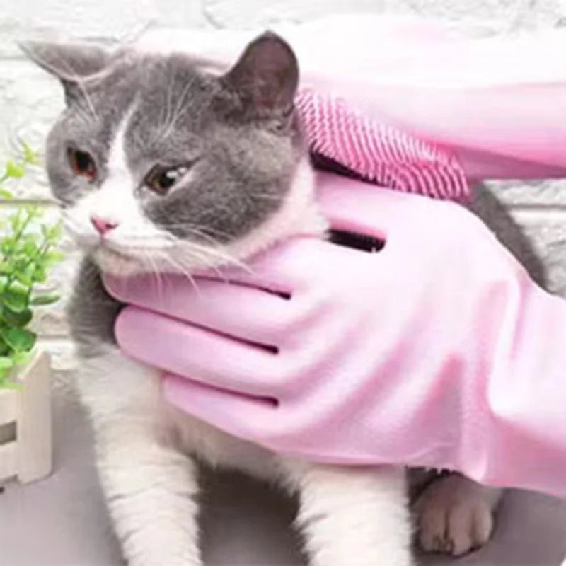 A gray and white cat is resting on a pink pet grooming glove.