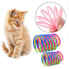 A small orange kitten sitting next to colorful spiral spring toys for cats and ferrets.