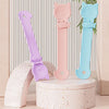 Ein Set aus drei langen, lickbaren Katzenfutterlöffeln in Lila, Pink und Blau auf einem weißen Ständer.