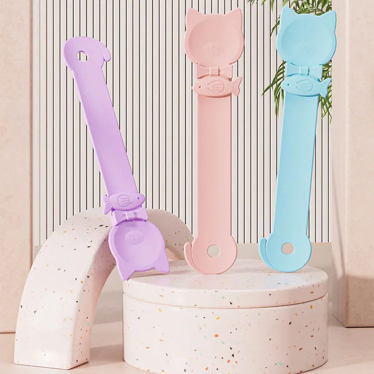 Ein Set aus drei langen, lickbaren Katzenfutterlöffeln in Lila, Pink und Blau auf einem weißen Ständer.