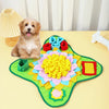 A golden-colored dog is sitting next to a green snuffle mat decorated with colorful fabric flowers.