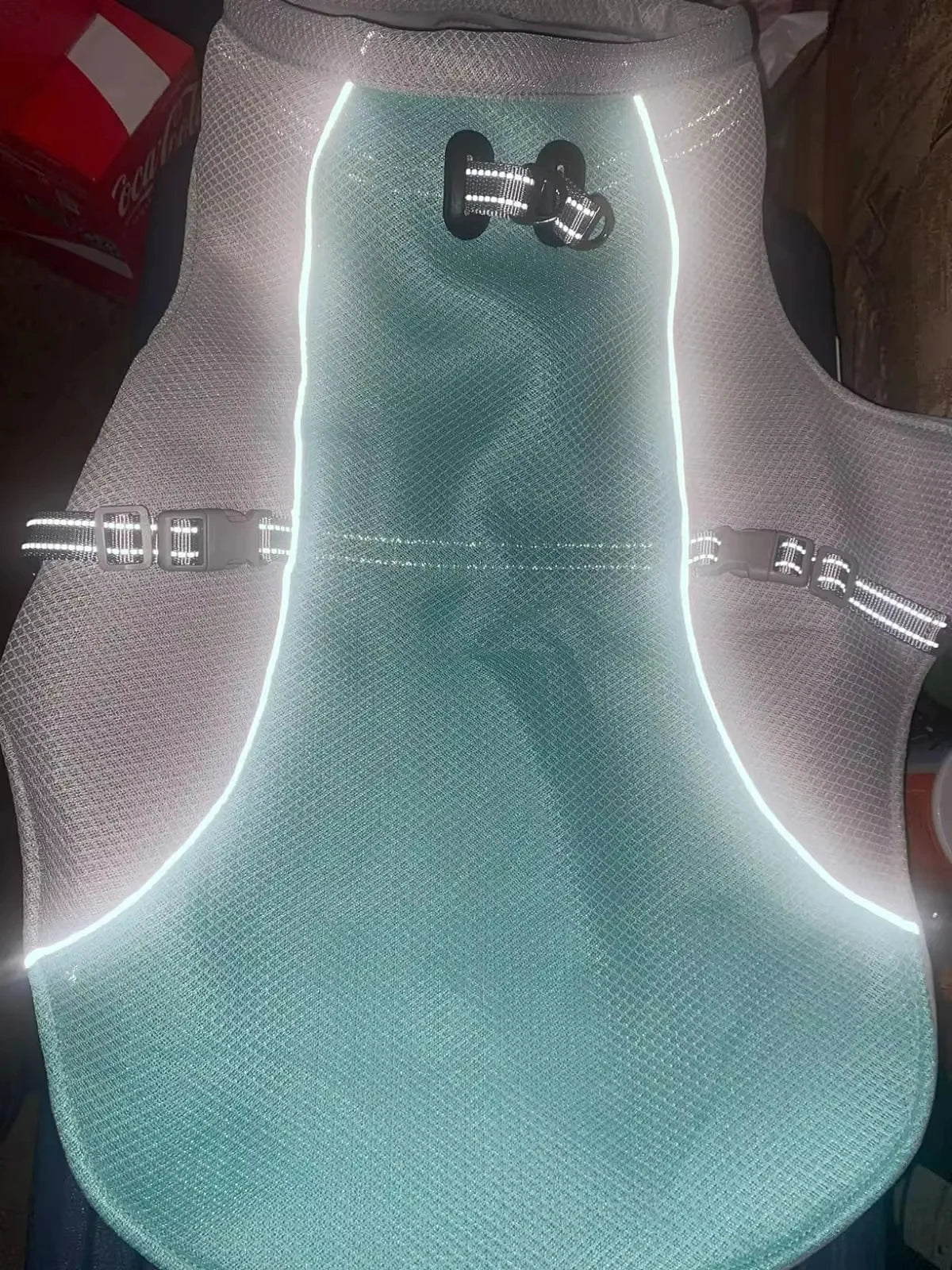 A light blue evaporative cooling dog vest with a reflective harness is displayed against a white background.