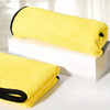 Serviette de bain pour animaux jaune vif ultra-absorbante, roulée sur un bloc blanc et une autre serviette pliée.