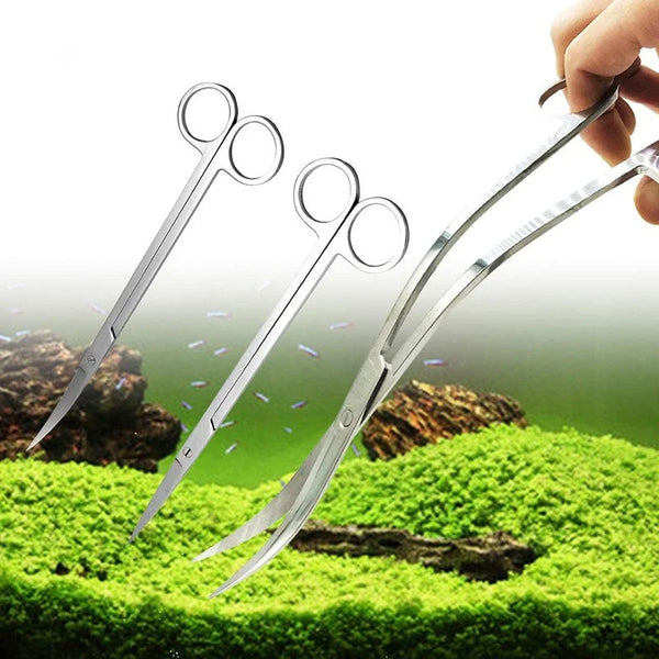 A hand holds a set of stainless steel aquarium cleaning tools with sharp blades and curved tips over green moss.